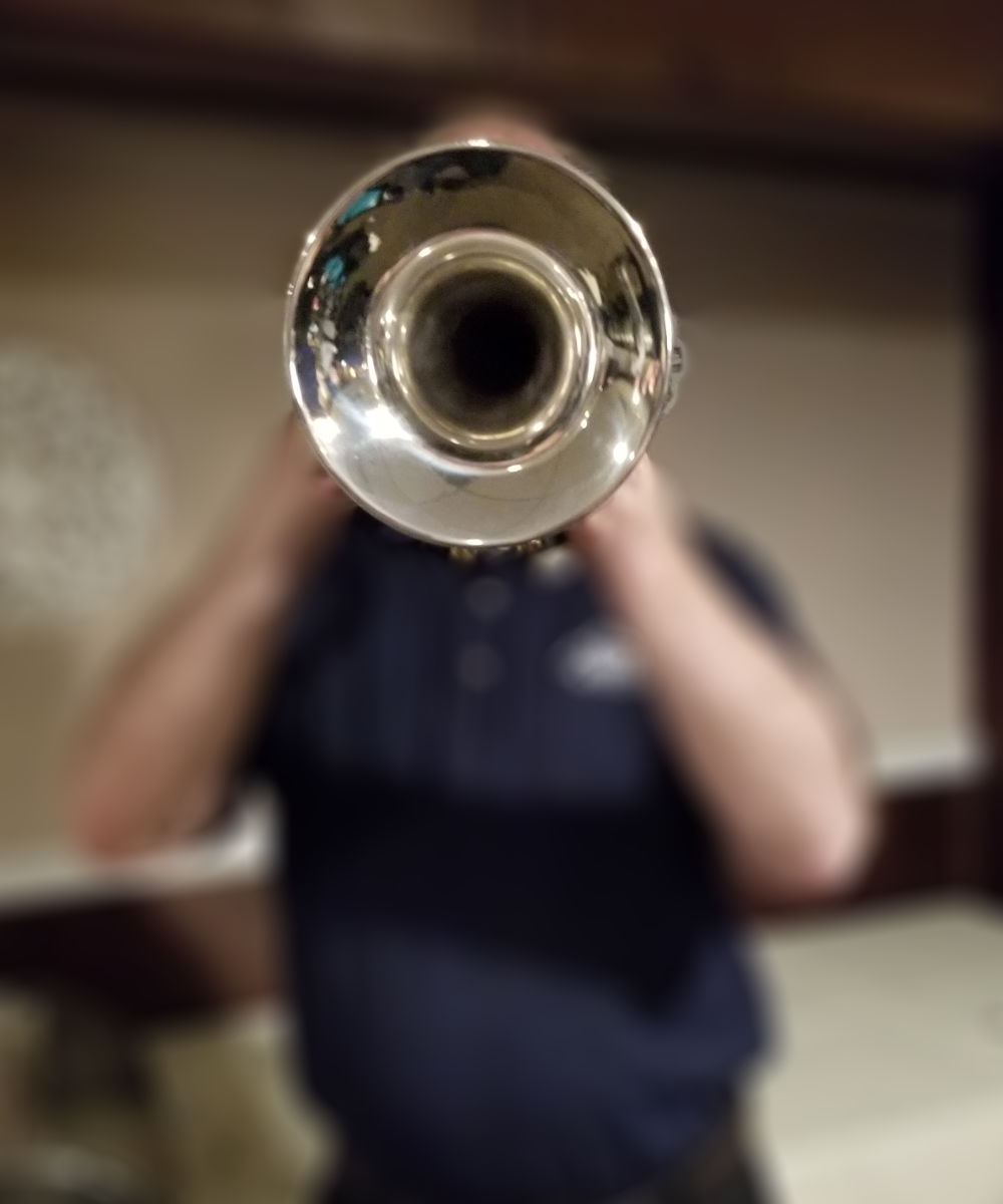 A trumpet obscuring a trumpeter